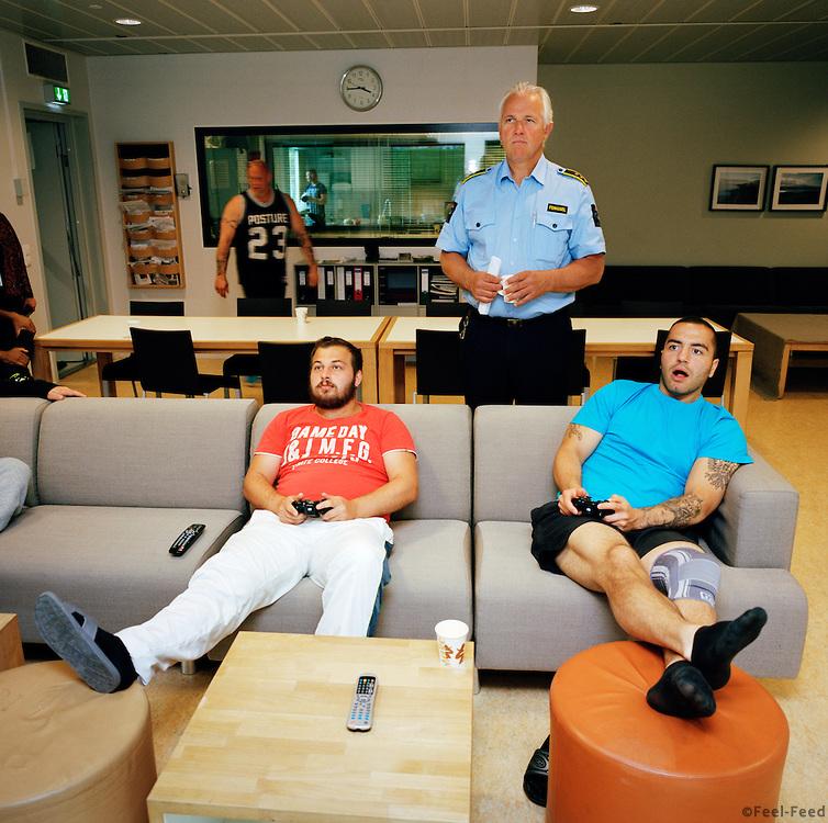 Halden Prison, Norway, June 2014: Inmates playing TV games on a large TV screen in the common area in C8, a special unit for addiction recovery. Governor Are Høidal standing. -- No commercial use -- Photo: Knut Egil Wang/Moment/INSTITUTE