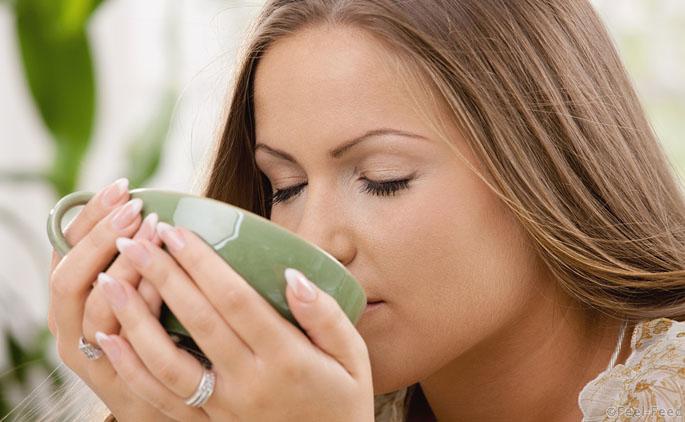 Closeup portrait of beautiful girl drinking tea from green cup.