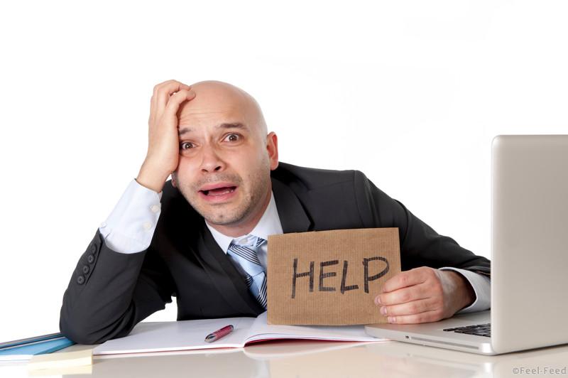 overworked unhappy bald business man in stress wearing suit holding help sign working on computer