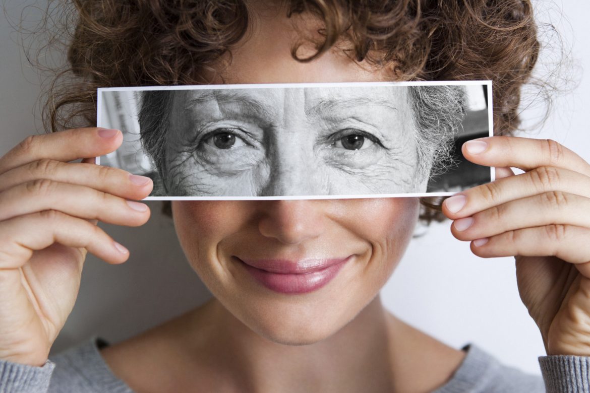Woman with photo of elderly woman's eyes on hers'