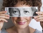 Woman with photo of elderly woman's eyes on hers'