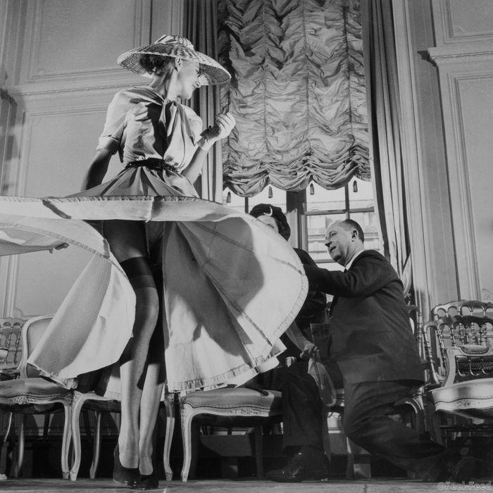 Original caption: Stockings were highlighted for the first time when Christian Dior (right), noted French designer, exhibited his French collection. The hose, which either continued the dress' color scheme from hem to ankles or afforded a direct contrast, ranged in shades from tender peach to ink black. The colors are called "Boulevard Banquet." Here a model swirls the skirt of a light blue crepe dress to feature the sheer navy blue stockings. March 11, 1948 Paris, France