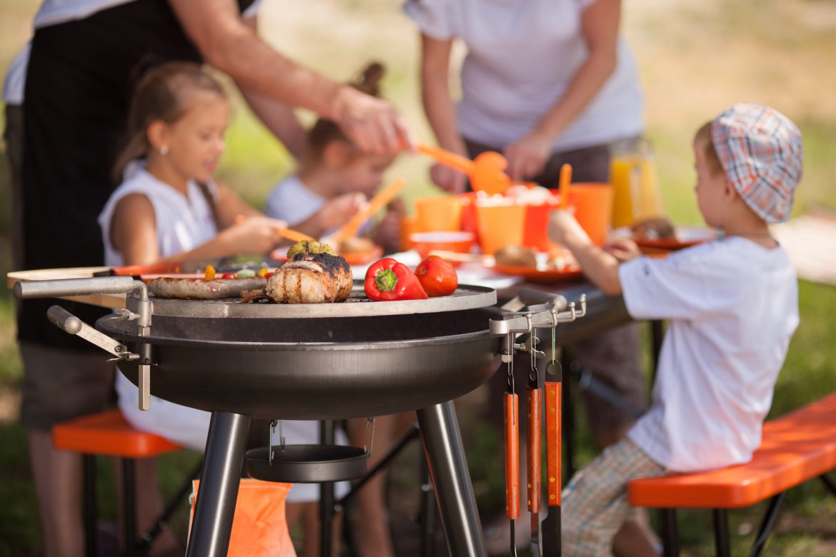 Family having a barbecue in the garden - focus on grilled food in the foreground