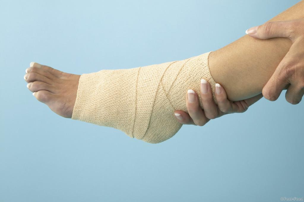 Woman Holding Bandaged Ankle --- Image by © Royalty-Free/Corbis