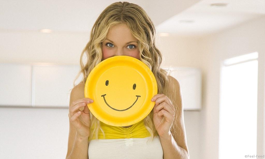 Young Woman Holding Smiley Face --- Image by © RCWW, Inc. /RCWW, Inc./Corbis