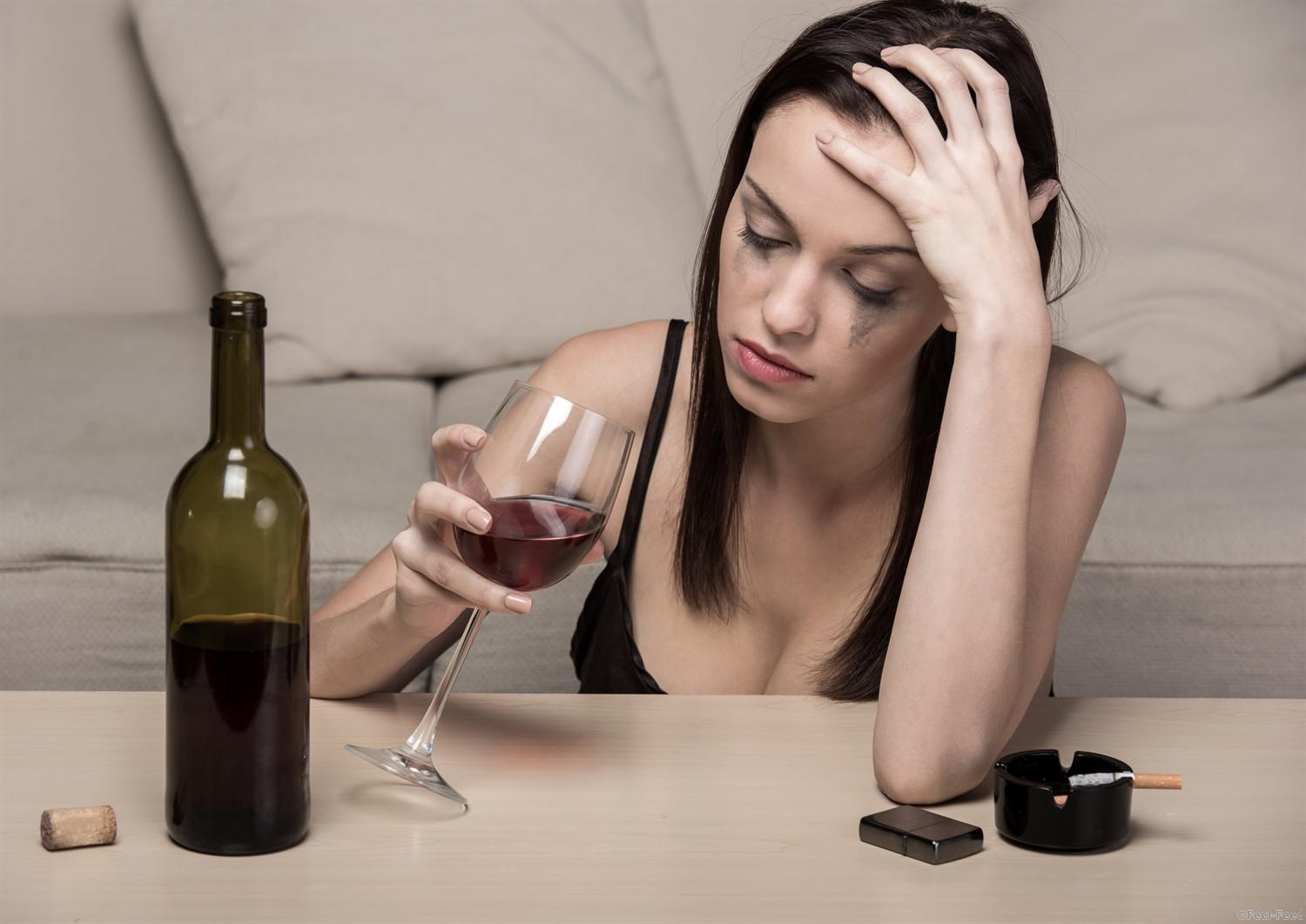 Young beautiful woman in depression, is drinking alcohol and smoking.