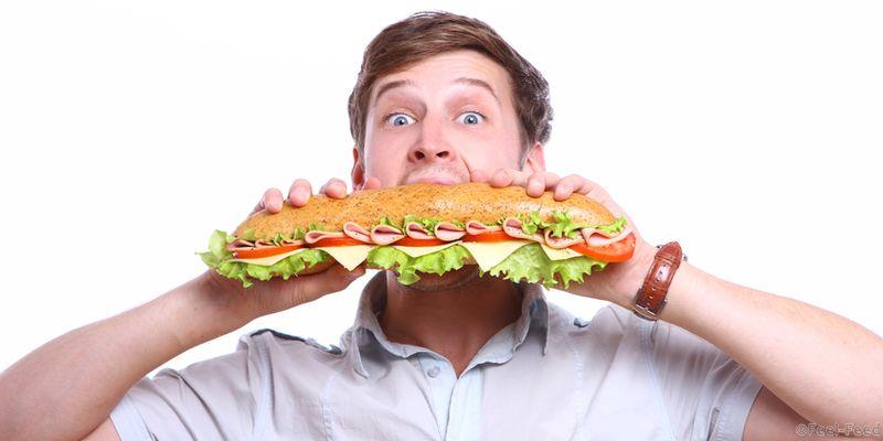 Young man with big sandwich isolated over white background