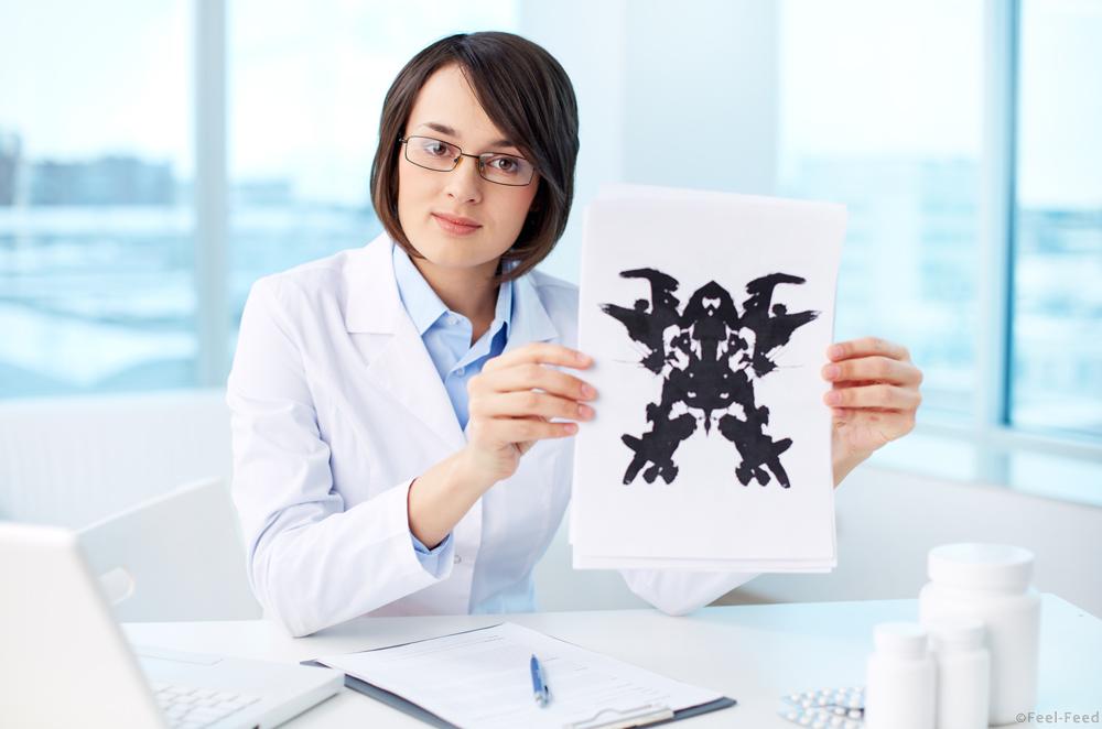 Serious psychologist showing paper with Rorschach inkblot
