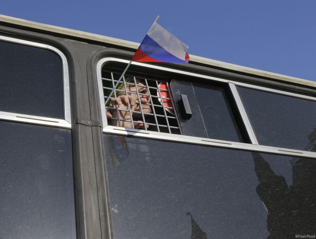 A participant waves a flag from a police bus after being detained at a rally to protest yesterday's sentencing of anti-corruption blogger and opposition leader Alexei Navalny, in Moscow March 1, 2014. A Russian court placed Navalny under house arrest for at least two months on Friday and barred him from using the Internet or speaking to the media. REUTERS/Tatyana Makeyeva (RUSSIA - Tags: CIVIL UNREST POLITICS TPX IMAGES OF THE DAY) - RTR3FUUO