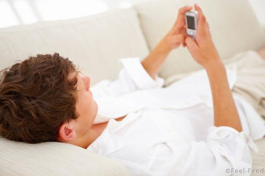 Closeup of young guy lying on sofa and using mobile phone
