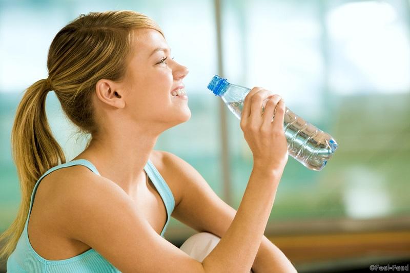 Profile of beautiful woman going to drink some water fron plastic bottle after workout